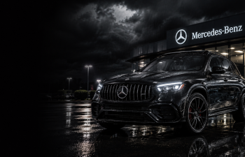 Black Mercedes-Benz SUV parked on wet pavement at night outside a dealership with the Mercedes-Benz sign illuminated under a dramatic cloudy sky.